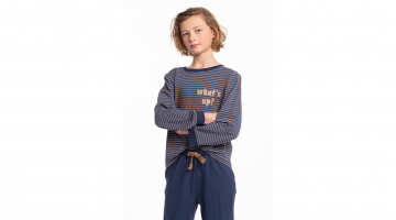 De Pyjama Saul van Eskimo voor jongens van 10 tot 14 jaar is een zachte en luchtige katoenen pyjama voor zoete dromen.  De T-shirt heeft lange mouwen, een ronde hals, allover strepen print, en tekst op de borst What's up!.  De effen donkerblauwe broek hee